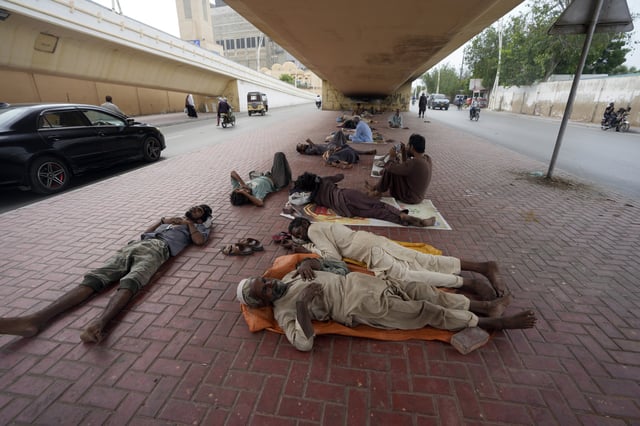 FILE - Laborers sleep under a bridge during a hot summer day in Karachi, Pakistan, Thursday, July 25, 2024. (AP Photo/Fareed Khan,File)