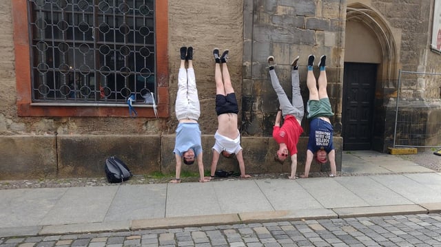 4 Männer vom Verein Lüner SV machen Handstand vor der Nikolaikirche in Leipzig.