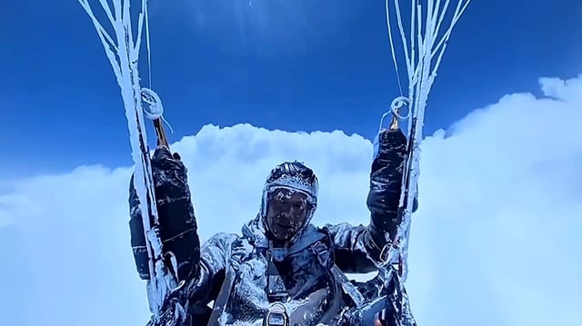 Peng Yujiang, 55, is seen paragliding, his body caked with ice.