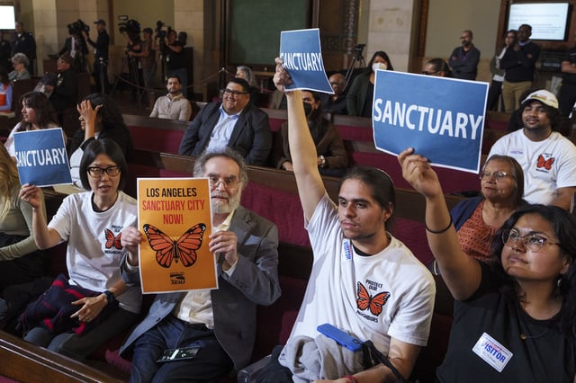 FILE - Members of immigration advocacy groups react as Los Angeles City Council votes to enact an ordinance to prohibit city resources from being used for immigration enforcement in anticipation of potential mass deportations under President-elect Donald Trump, inside Los Angeles City Hall on Tuesday, Nov. 19, 2024. (AP Photo/Damian Dovarganes, File)