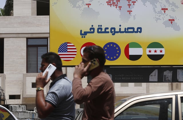 Syrian men speak on their phones on a street in Damascus, Syria, Wednesday, May 14, 2025. (AP Photo/Omar Sanadiki)
