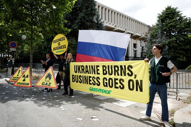 Greenpeace activists hold a banner which reads "Ukraine burns, business goes on" next to a wax statue of French President Emmanuel Macron borrowed from the Grevin Museum without permission, to denounce what they call France's continued commercials ties with Russia despite the war in Ukraine, in front of the Russian Embassy in Paris, France, June 2, 2025. REUTERS/Benoit Tessier