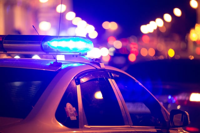 Stock image of a police car flashing its lights at night.
