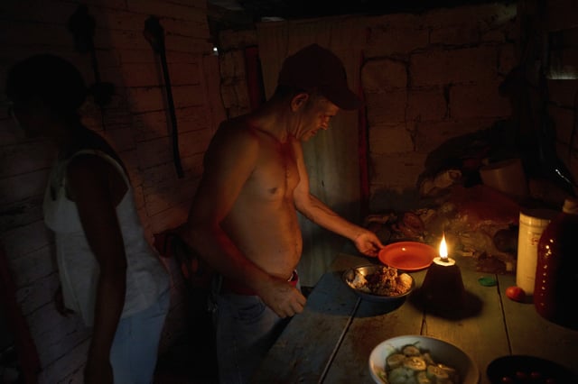 Edinector Vazquez prepares to eat dinner at his home lit by a gas lamp during a blackout in Minas, Havana province, Cuba, Monday, May 26, 2025. (AP Photo/Ramon Espinosa)