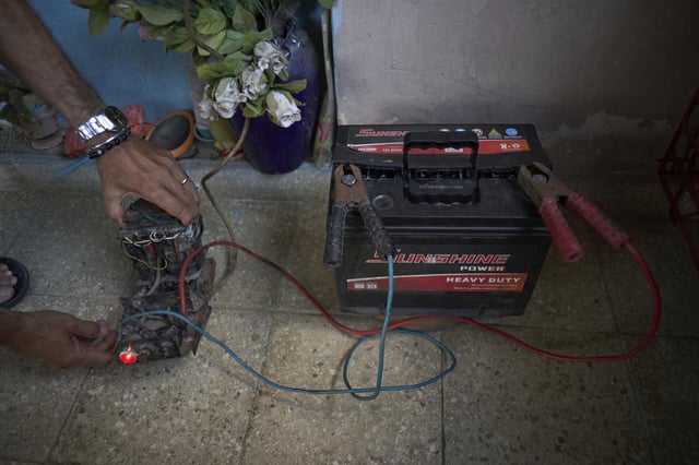 Angel Rodriguez uses a transformer from an old television to charge a battery in preparation for blackouts at his home in the Bahia neighborhood of Havana, Cuba, Monday, May 26, 2025. (AP Photo/Ramon Espinosa)