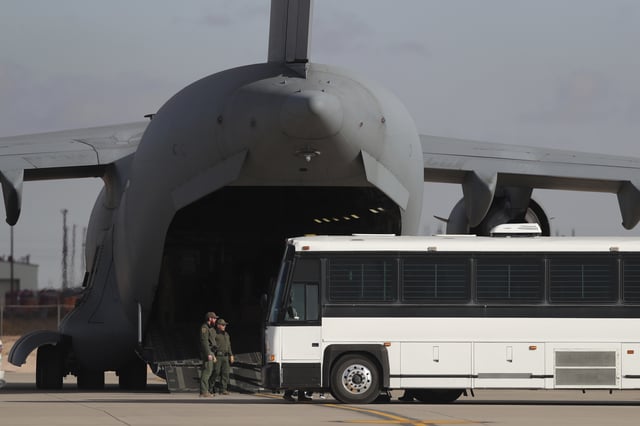 FILE - A military aircraft waits for migrants to board from a bus at Fort Bliss in El Paso, Tx., Thursday, Jan. 30, 2025, before deporting them to Guatemala. (AP Photo/Christian Chavez, File)