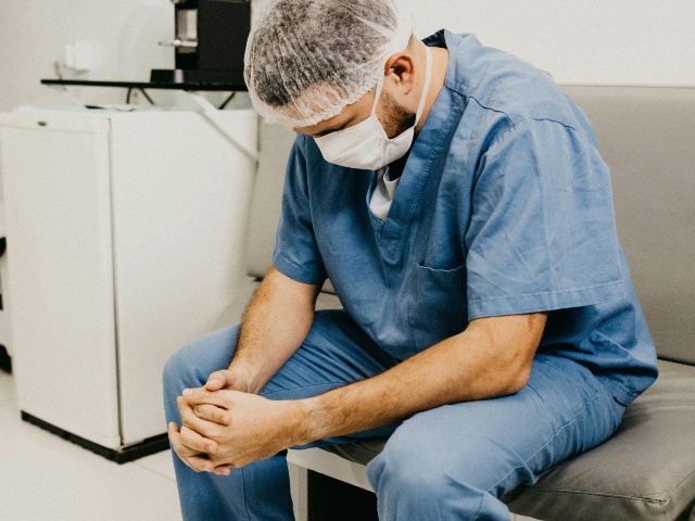 man in scrubs praying