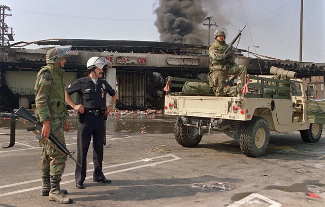 National Guardsmen and a police officer take up security positions in front of a burned and looted shopping center, May 1, 1992, in central Los Angeles. The 1992 Los Angeles protests erupted April 29, 1992, when a mostly White jury acquitted four police officers of beating Black motorist Rodney King.