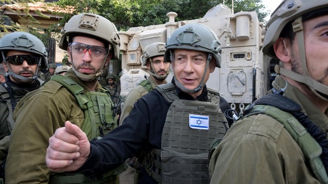 Israeli Prime Minister Benjamin Netanyahu, center, wears a protective vest and helmet as he receives a security briefing with commanders and soldiers in the northern Gaza Strip, on Monday, Dec. 25, 2023. (Avi Ohayon/GPO/Handout via AP)