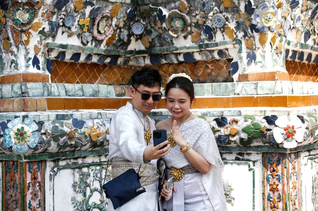 Chinese tourists dressed in rented Thai costumes pose for photographs at the Temple of Dawn in Bangkok last month. Photo: EPA-EFE