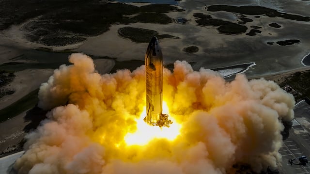 a rocket on a launch pad fires its engines, creating a massive plume of fire and smoke