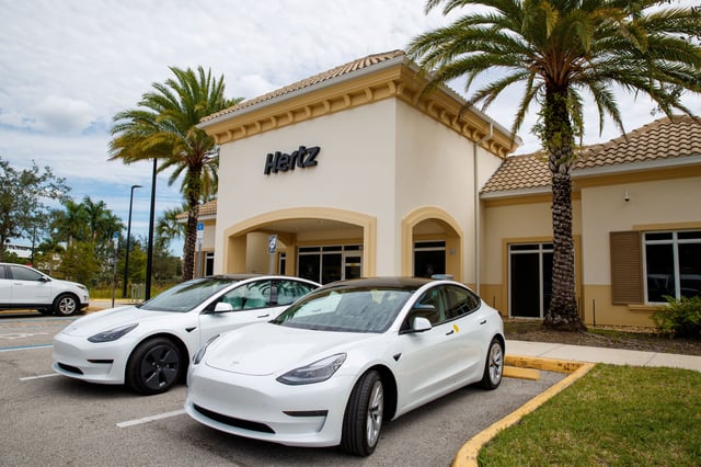 Tesla parked in front of Hertz office.