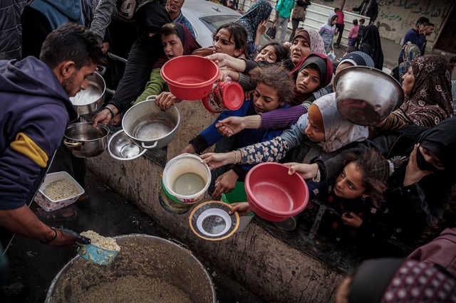 Palestinians wait to collect food at a donation point in a refugee camp in Rafah in the southern Gaza Strip on December 23, 2023, amid continuing battles between Israel and the militant group Hamas.