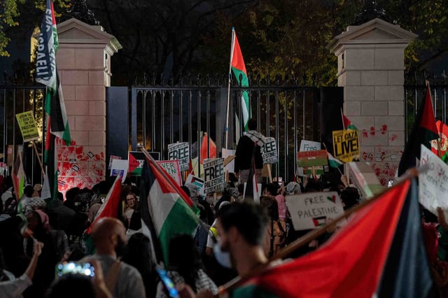 Demonstrators leave red hand prints on the fence in front of the White House during a rally in support of Palestinians in Washington, DC, on November 4, 2023.