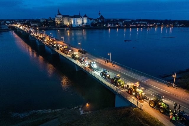 Tractors drive past Hartenfels Castle and cross the river Elbe in Torgau, eastern Germany.
