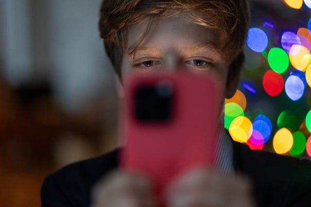A 12-year-old boy looks at an iPhone screen on December 19, 2023, in Bath, England.