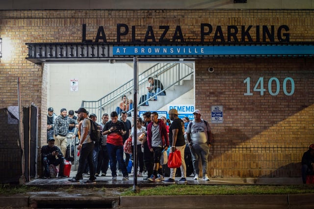Migrants stand at a processing center as they wait for a bus to Chicago, in downtown Brownsville, Texas, on October 24, 2023.