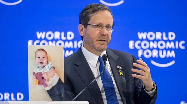 Israeli President Isaac Herzog speaks next to a photograph showing 10-month-old baby Kfir Bibas held by Hamas during a session of the World Economic Forum (WEF) meeting in Davos on January 18, 2024.