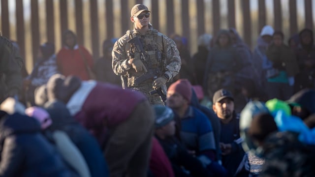 A U.S. Customs and Border Protection (CBP) officer seen surrounded by migrants in Lukeville, Arizona on Dec. 5 2023