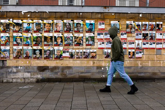 A person walks past a wall in Tel Aviv, Israel, on Friday with pictures of hostages who were captured by Hamas on October 7. Photo: Reuters