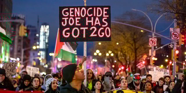 A Palestine solidarity protester carries a sign that reads “Genocide Joe has got 2 go,” while marching over the Williamsburg Bridge in New York City on Dec. 4, 2023.