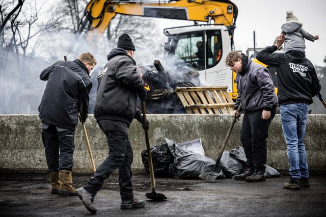 Belgian farmers clean the road surface while blocking the border crossing between Belgium and Netherlands in Arendonk on Saturday. Photo: EPA-EFE