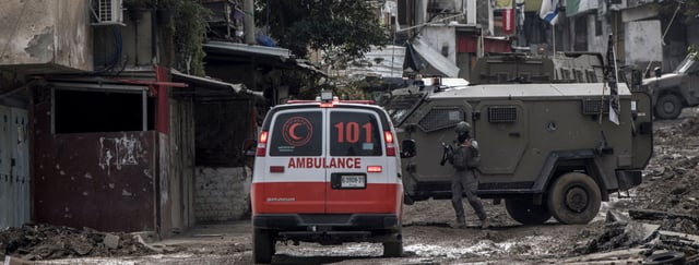 TOPSHOT - CORRECTION / An Israeli soldier gestures towards a Palestinian Red Crescent ambulance at the entrance of the Tulkarem refugee camp in Tulkarem, in the occupied West Bank, on January 17, 2024 during a military operation. (Photo by MARCO LONGARI / AFP) / "The erroneous mention appearing in the metadata of this photo by MARCO LONGARI has been modified in AFP systems in the following manner: [Red Crescent ambulance] instead of [Red Cross ambulance]. Please immediately remove the erroneous mention from all your online services and delete it from your servers. If you have been authorized by AFP to distribute it to third parties, please ensure that the same actions are carried out by them. Failure to promptly comply with these instructions will entail liability on your part for any continued or post notification usage. Therefore we thank you very much for all your attention and prompt action. We are sorry for the inconvenience this notification may cause and remain at your disposal for any further information you may require." (Photo by MARCO LONGARI/AFP via Getty Images)