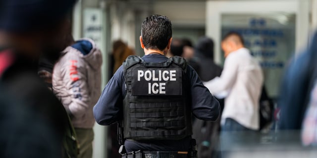 An ICE agent monitors hundreds of asylum seekers being processed on June 6, 2023 in New York City.