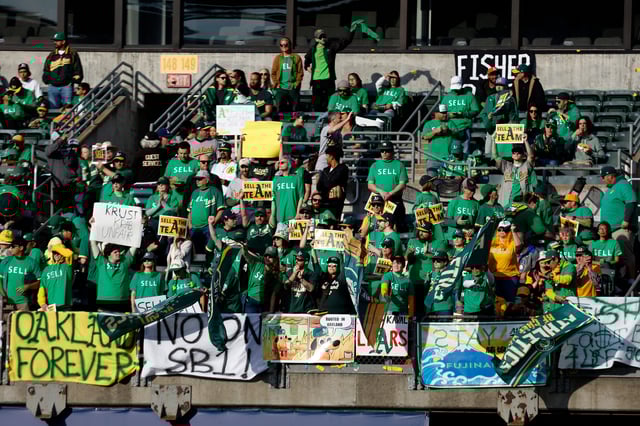 Fans hold signs at Oakland Coliseum to protest the Oakland Athletics' planned move to Las Vegas.