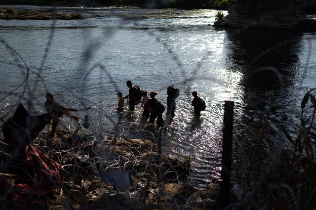 Migrants walking in the Rio Grande looking for a break in the razor wire at the US-Mexico border in Eagle Pass, Texas, on September 23, 2023.