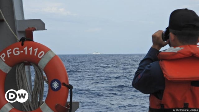 A Taiwanese naval soldier looks through binoculars at a Chinese naval ship