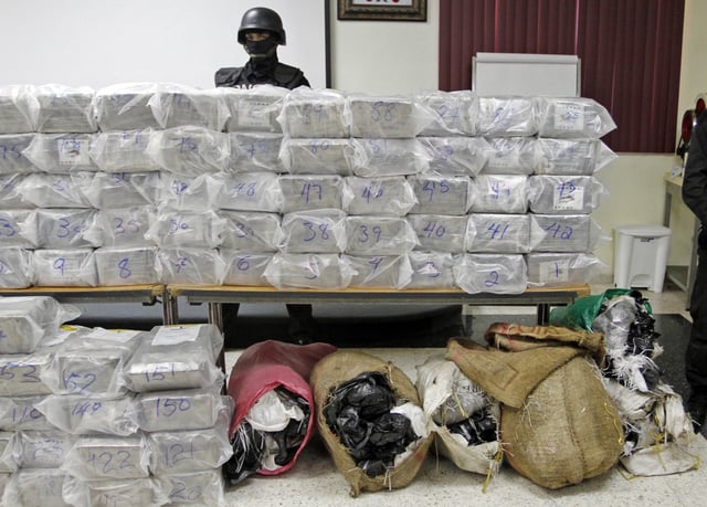 A Dominican anti-drug police officer stands behind packages of seized drugs during a news conference at the National Drug Control Agency in Santo Domingo, Dominican Republic. The Dominican Republic is now the region's biggest transit point for drugs. A U.S. military assessment projected that 6 percent of the cocaine destined for the U.S. this year will pass through the Dominican Republic alone. (AP Photo/Manuel Diaz) | Manuel Diaz