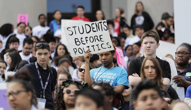 A student from Destiny Charter Middle School in Tacoma, Wash., holds a sign that reads "Students Before Politics," during a rally held by charter school students, teachers, and supporters at the state Capitol on May 17, 2018.