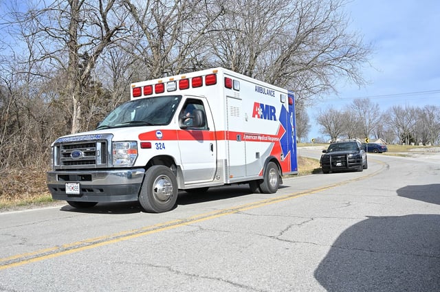 An ambulance and a police car leave the scene of the shooting in Independence, Missouri.
