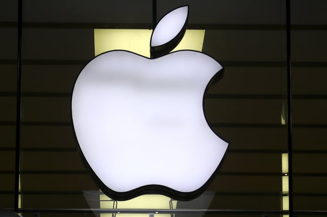 The Apple logo is illuminated at a store in the city center of Munich, Germany, Dec. 16, 2020. European Union fines Apple nearly $2 billion for unfairly favoring its own music streaming service over rivals. (AP Photo/Matthias Schrader, File)