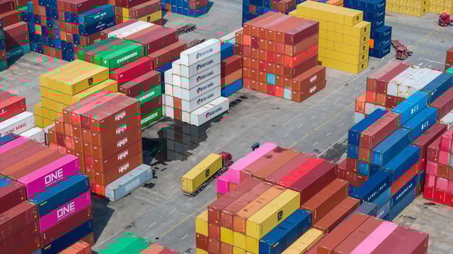 Container cranes unload containers from a cargo ship as trucks shuttle through a container yard at Longtan Container Terminal in Nanjing, Jiangsu province, China.
