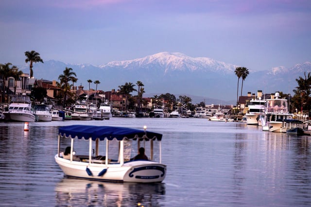 The setting sun illuminates clouds and the top of recently snow-capped San Gabriel mountains above Huntington Harbour in Huntington Beach on Friday, Feb. 23, 2024. Officials began work Friday to clean up an oil patch spotted a few miles off the coast of Huntington Beach. 
