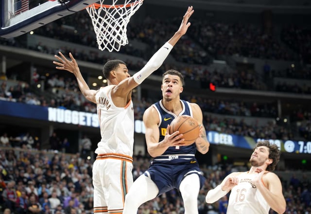 Denver Nuggets forward Michael Porter Jr., center, drives to the basket between San Antonio Spurs center Victor Wembanyama, left, and forward Cedi Osman, right, in the second half of a Nov. 26, 2023 game in Denver.