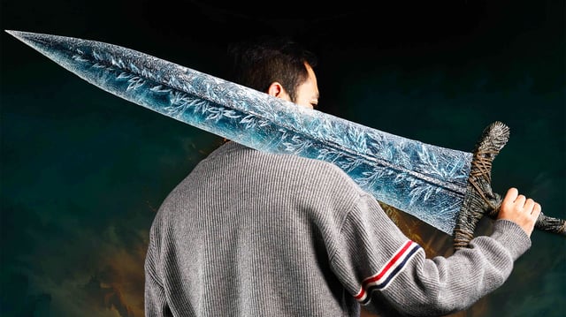 A person holding a replica of Elden Ring's Dark Moon Greatsword over their shoulder