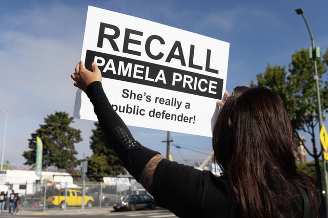 Barbara Nguyen hold a recall sign at a recall drive calling on the removal of Alameda County District Attorney Pamela Price in Oakland in October.