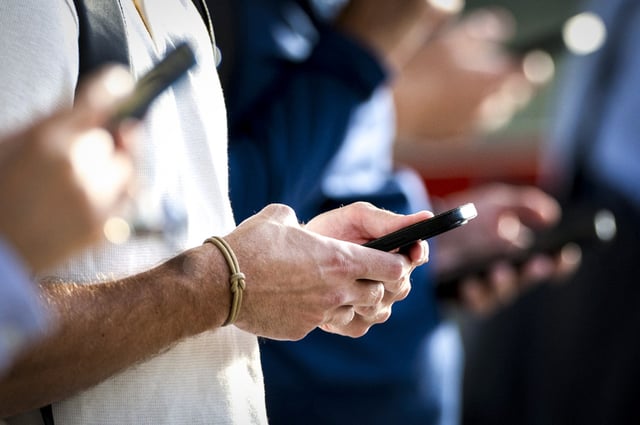People check their phones on Aug. 28, 2023, in Stamford, Conn. 