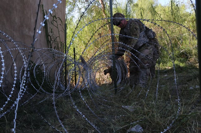 soldier puts up wire along border in Texas