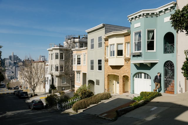 A person stands outside homes on Greenwich and Child Street in Telegraph Hill in San Francisco on Friday, Feb. 9, 2024. Luxury home sales were significantly down in 2023 and experienced real estate brokers have theories about macro economics, changing attitudes, and the San Francisco housing crisis.
