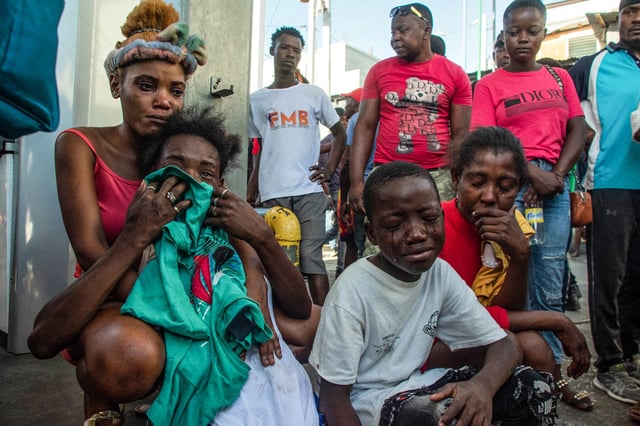 People react after a dozen of people were killed in the street by gang members, in Pétion-Ville, Port-au-Prince, Haiti, March 18, 2024.