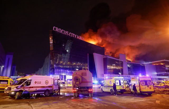 Vehicles of Russian emergency services are parked near the burning Crocus City Hall concert venue following a reported shooting incident, outside Moscow, Russia, on March 22.