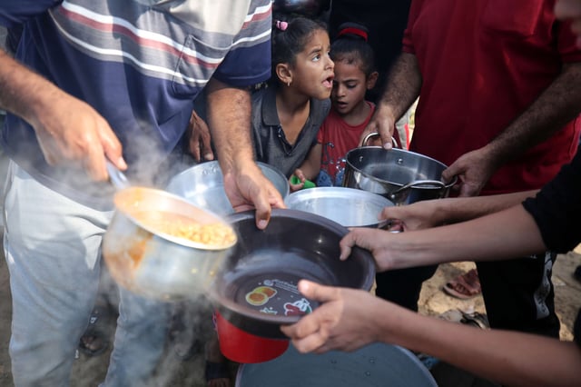 Palestinian children receive food at refugee center in Gaza