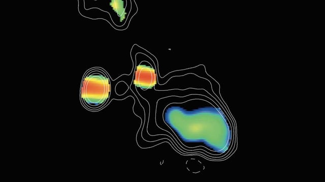 This image, taken by the Very Long Baseline Array (VLBA), shows two supermassive black holes, which appear as the blobs with red strips. The black holes are in the center of an elliptical galaxy. Colors represent different spectral slopes in radio emission, with red showing the most dense regions surrounding the black holes. The black hole on the right has likely recently devoured a massive star, which caused it to shoot out two ultrafast jets. The ends of those jets appear as green blobs above and below the black hole. This object, called J0405+3803, is referred to as a Compact Symmetric Object (CSO), because its jets are relatively close-in (or compact), compared to other black holes with much larger jets. Credit: H.L. Maness/Grinnell College