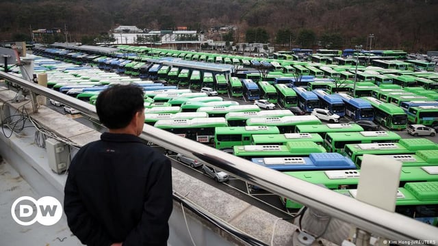A bus driver looks at buses parked at a depot, as bus drivers go on strike, in Seoul.
