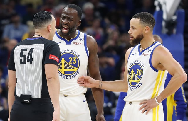The Golden State Warriors' Draymond Green (23) screams at game official Ray Acosta (54) as teammate Stephen Curry (30) steps in at right during action against the Orlando Magic at the Kia Center on Wednesday, March 27, 2024, in Orlando, Florida.