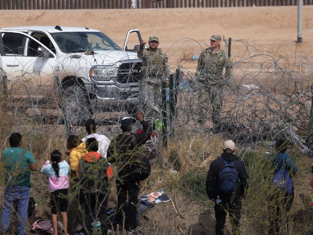 Texas National Guard agents prevent migrants from Venezuela from crossing a barbed wire fence to at the El Paso Sector Border after crossing the Rio Grande from Ciudad Juarez, Chihuahua state, Mexico, on February 29, 2024. US President Joe Biden and former President Donald Trump both visited the US-Mexico border in Texas today, in Brownsville and Eagle Pass, respectively. (Photo by Herika Martinez / AFP)